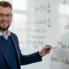 Fokusert lærer ved tavlen forklarer komplekse skolefag